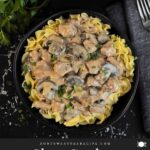 Slow Cooker Beef Stroganoff in a black bowl, garnished with chopped parsley.