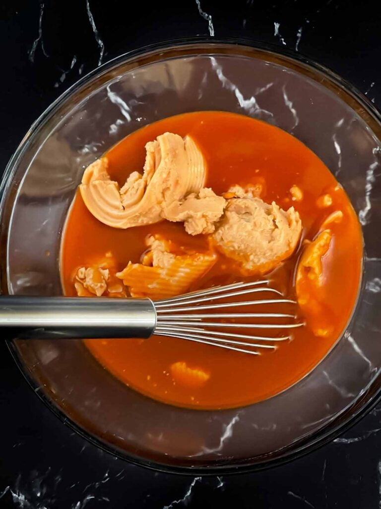 Refried beans and enchilada sauce in a glass bowl.