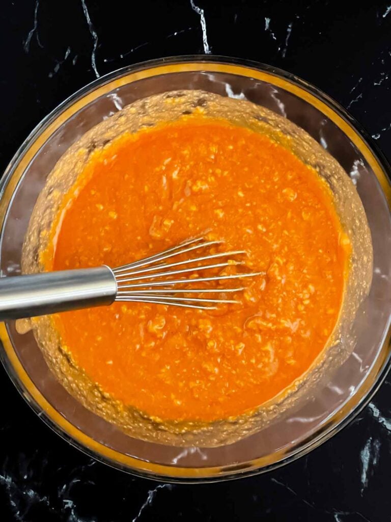 Refried beans and enchilada sauce in a glass bowl.